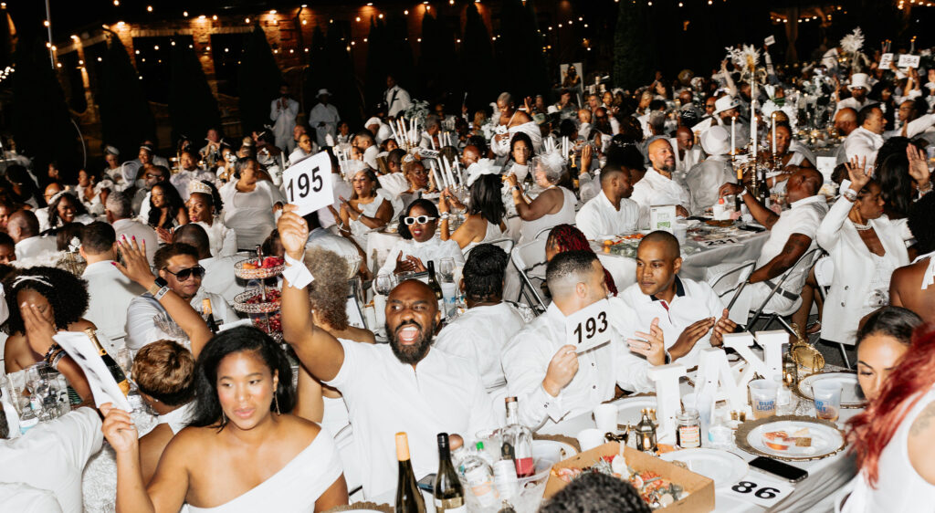 Large crowd dressed in white celebrating together during a high-energy professionally produced event.
